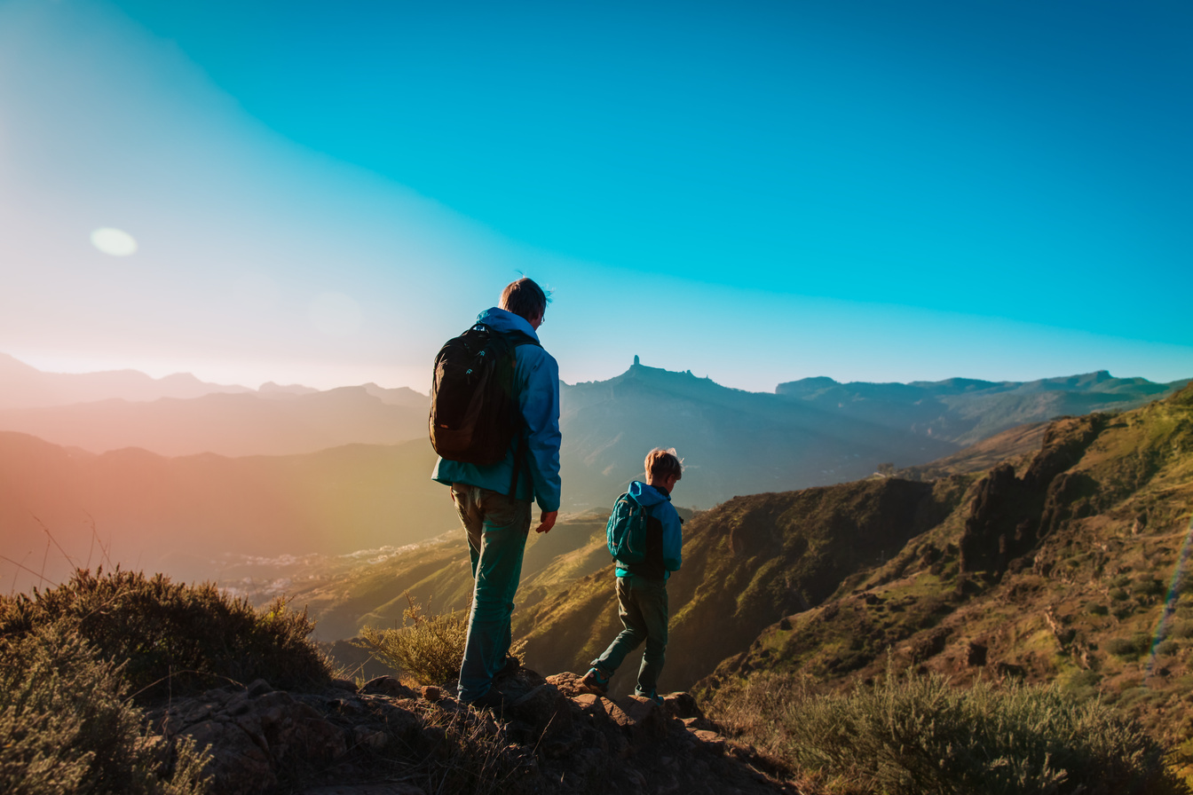 father and son hiking in sunset mountains, family travel
